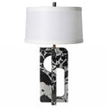 Table lamp with a black and white patterned base and a white shade on a white background